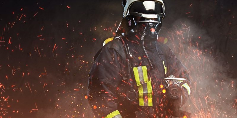 A firefighter dressed in a uniform in a studio.